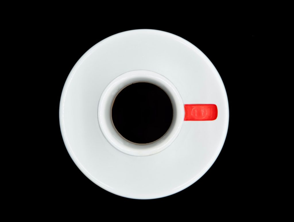 a white coffee cup with a red handle